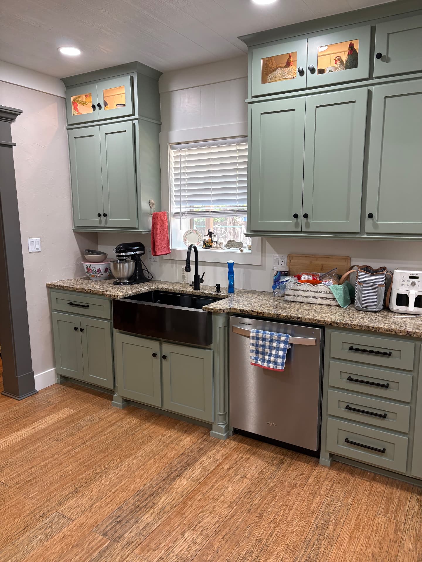 Finished kitchen sink wall with sage-green custom cabinetry