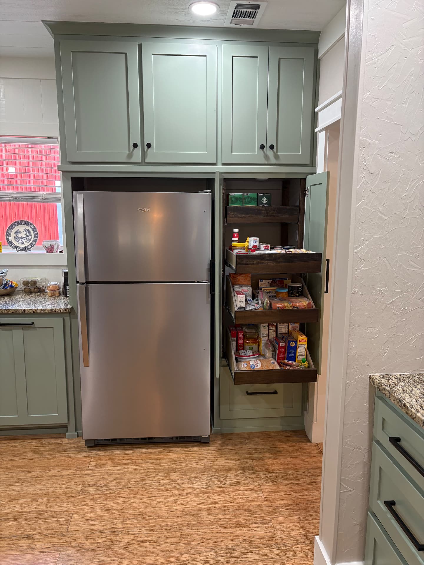 Built-in pantry with pull-out shelving next to refrigerator