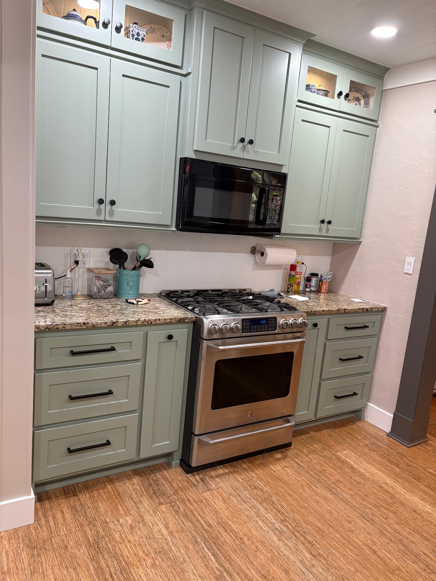 Finished kitchen range wall with sage-green custom cabinetry